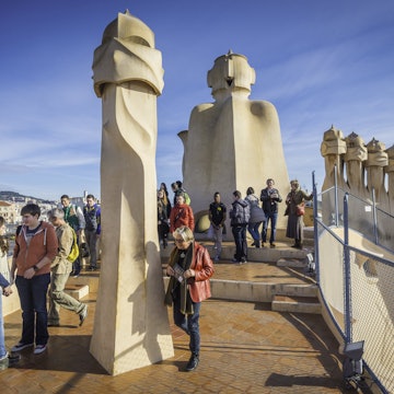 Barcelona, Spain - 14th February 2013: Tourists enjoying their visit to the rooftop of Casa Mila, La Pedrera, to see the iconic Gaudi chimneys that overlook the Sagrada Familia and the heart of downtown Barcelona, Spain.
